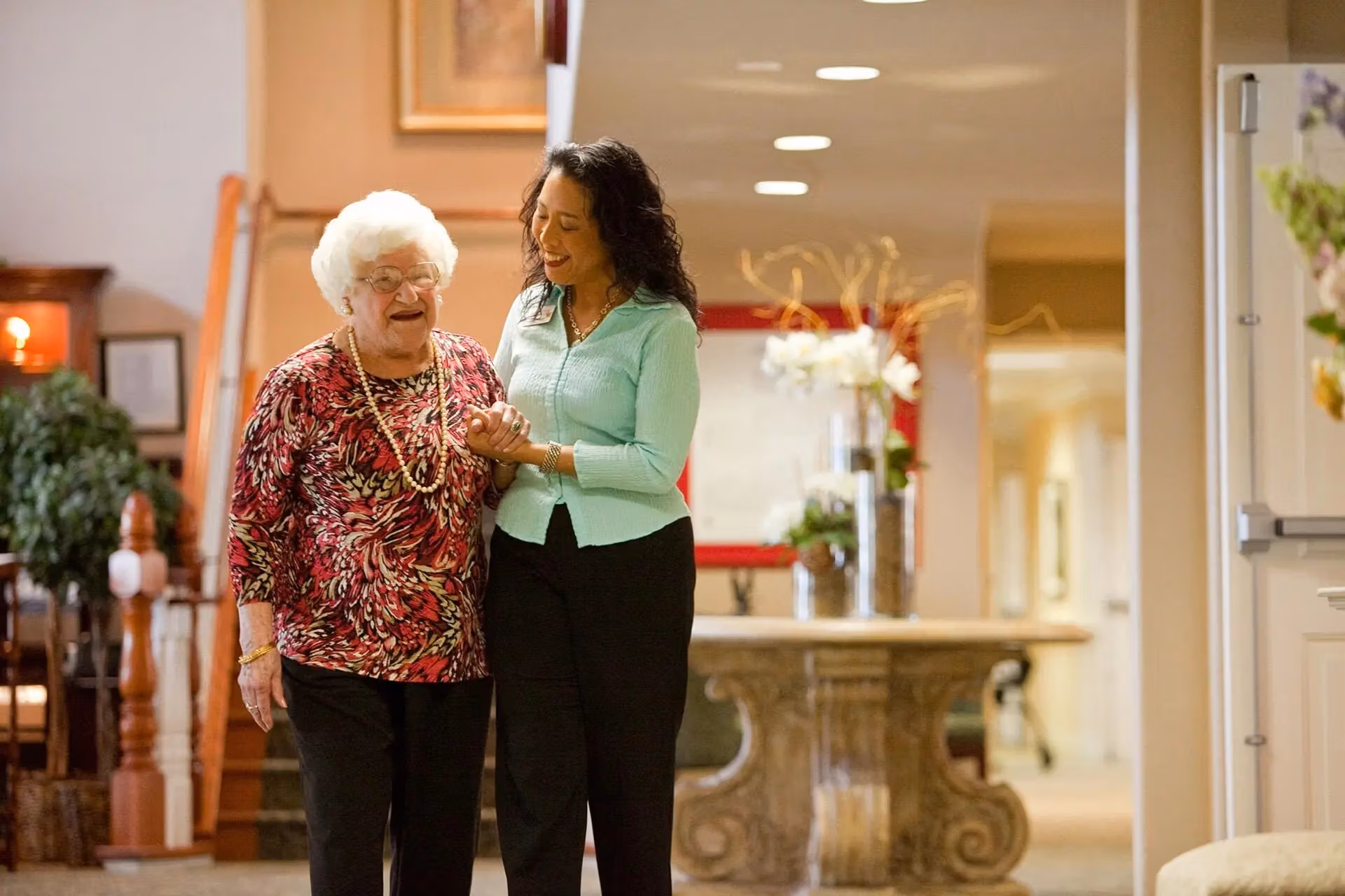An Áegis Living team member walking arm-in-arm with a resident through the community