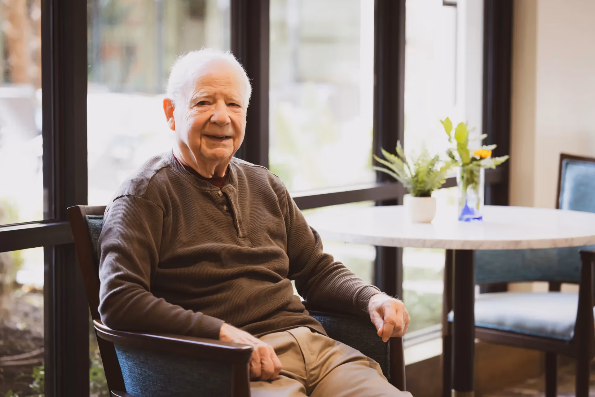 A resident enjoying quiet time at a sunlit table in his apartment