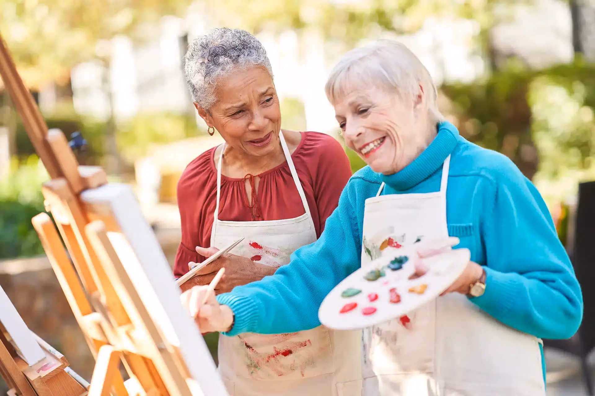 Two residents painting together during an outdoor art class