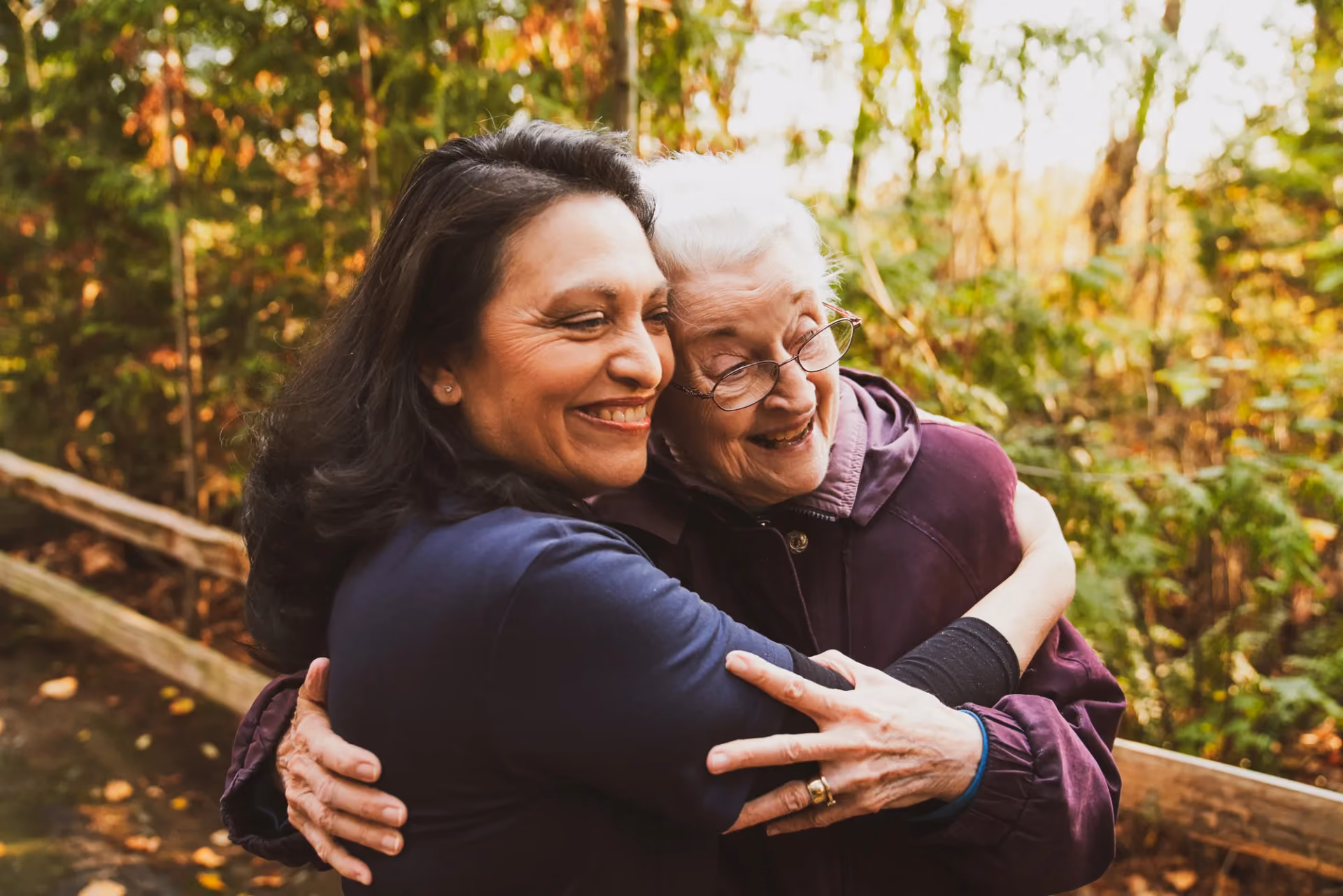 A caregiver and resident sharing a joyful hug outdoors