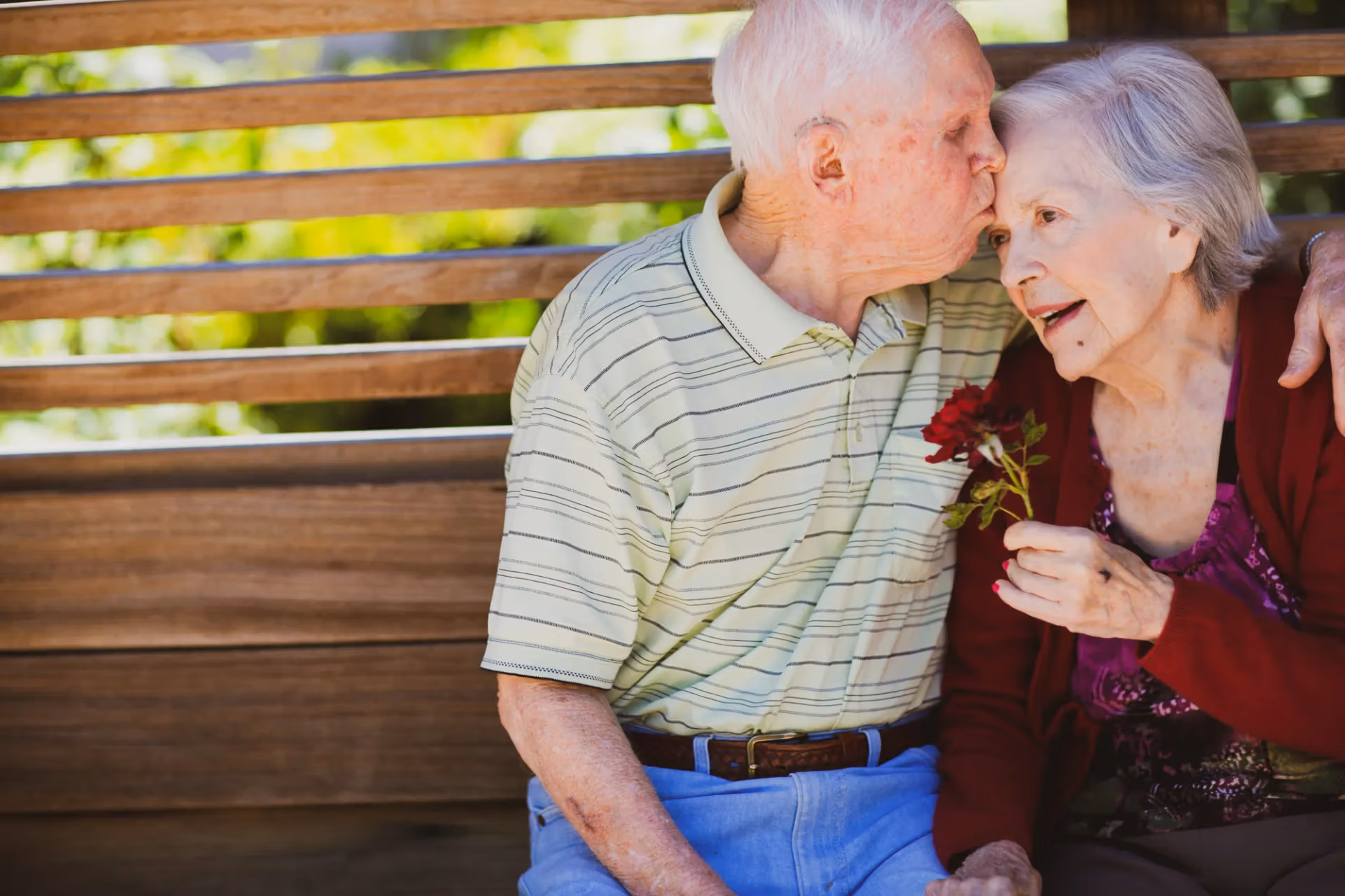 A resident couple sharing a tender moment on a garden bench