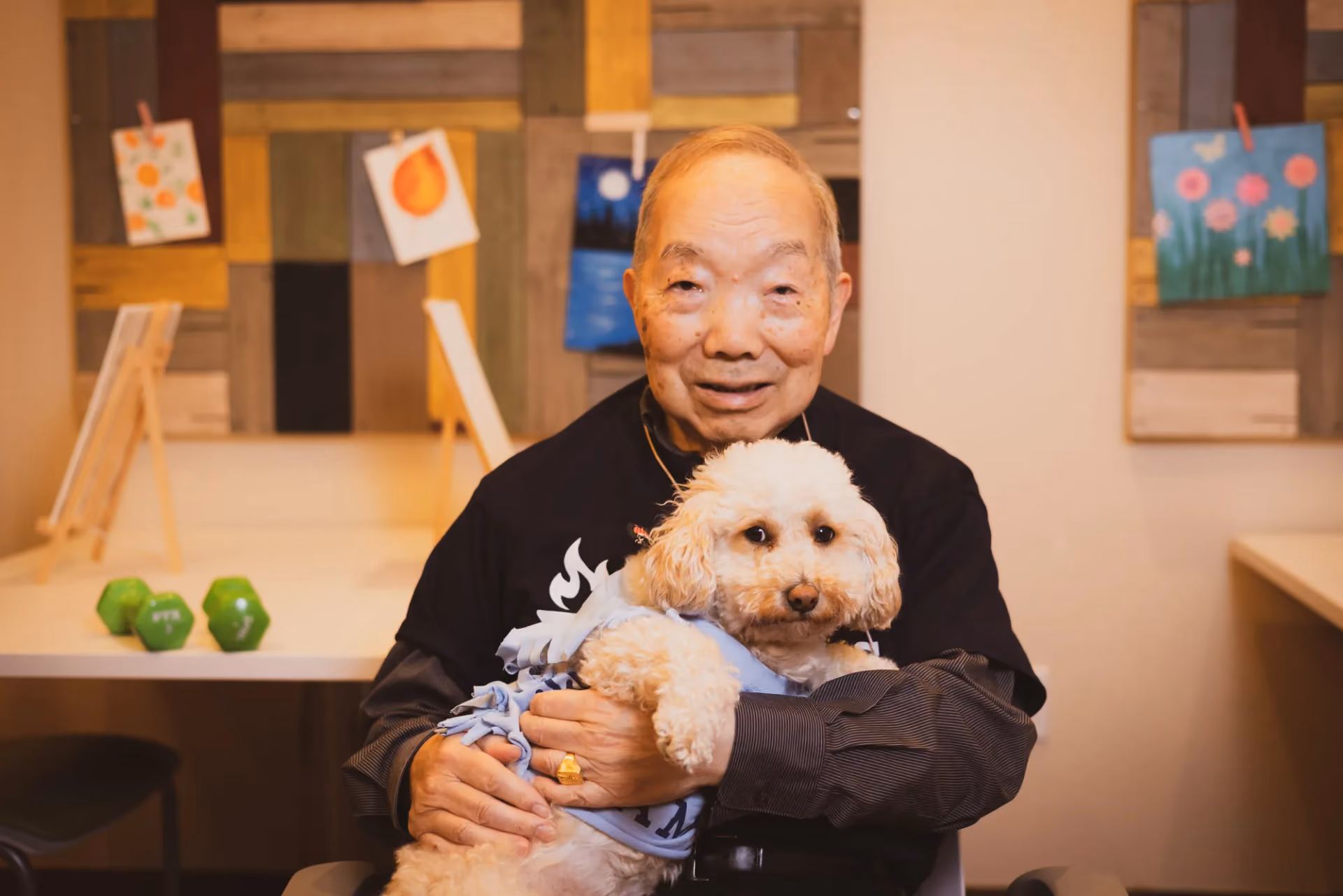 A resident cradling his poodle companion in the community lounge