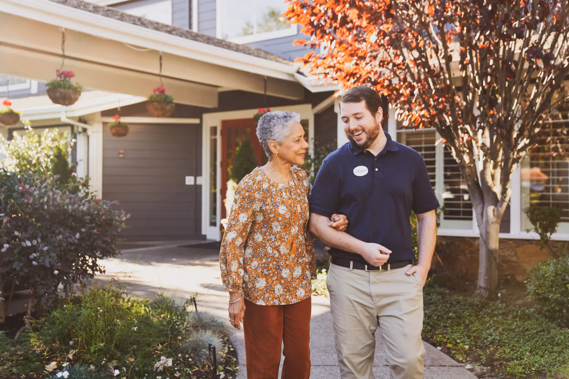 A team member walking arm-in-arm with a resident outside the community entrance