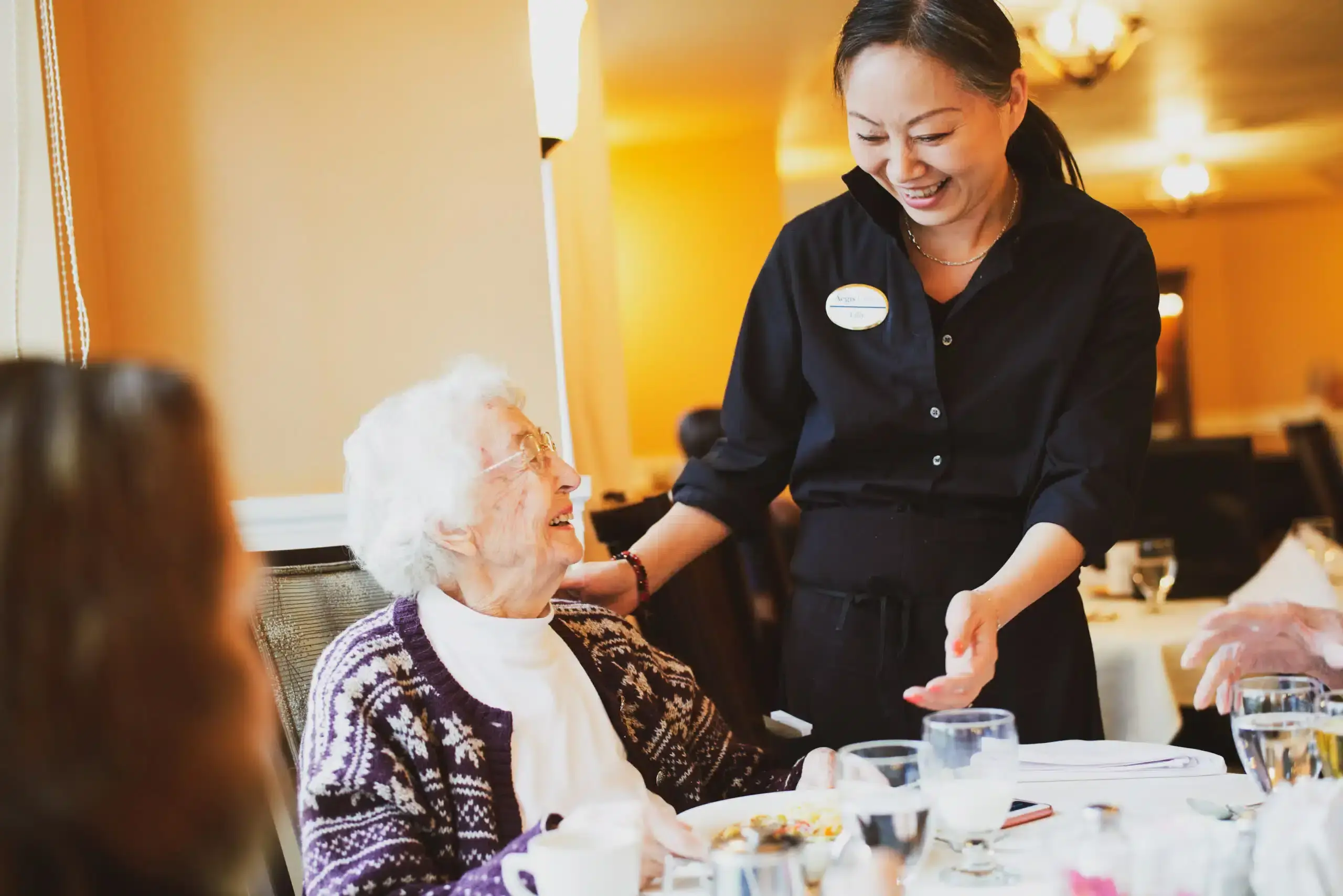 Bright dining hall with residents and servers